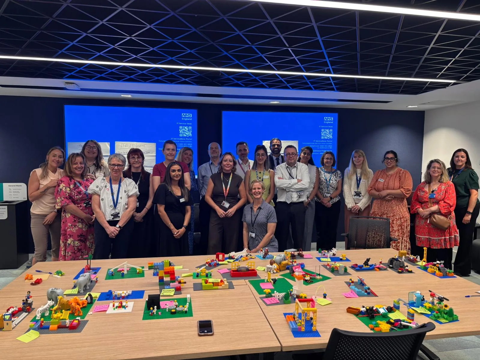 NHS England workshop team standing behind their completed LEGO® models